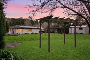 Ein Wohnhaus mit Veranda und kleinem Gartenhaus.