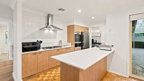 A modern kitchen with a central island, built-in oven, and stainless steel appliances. - Casa Cypress, Home Near Bowral with Garden and BBQ (Bowral)