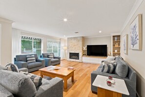 Ein modernes Wohnzimmer mit Kamin, Flachbildfernseher und einer Wand aus Naturstein.