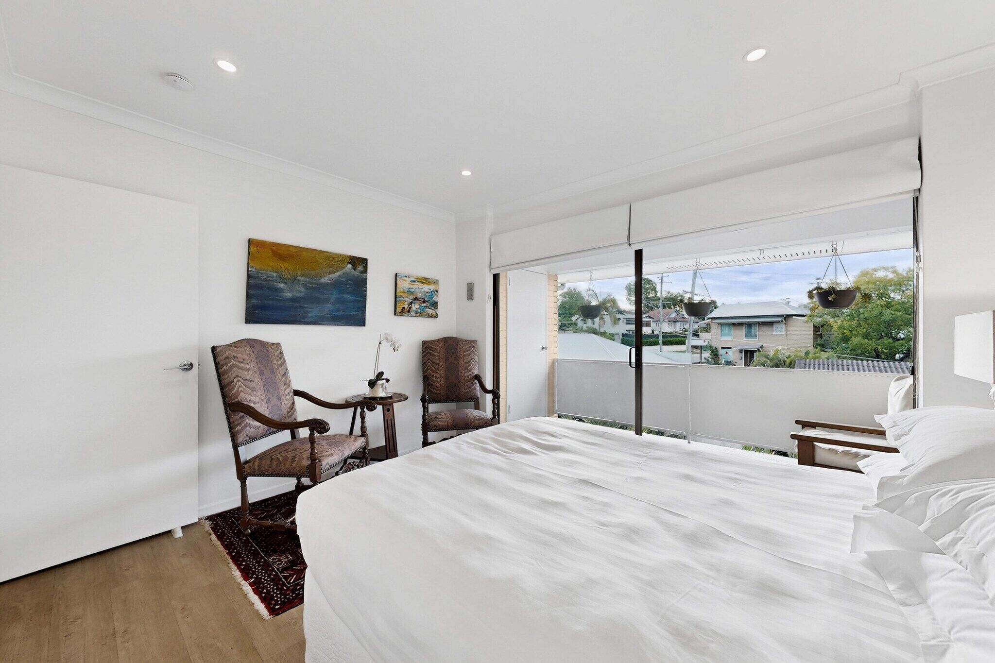 A hotel room with a large bed, two chairs, a small table, and a window with a view of the outside.