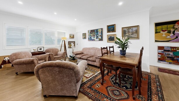 A living room with a sofa set, a dining table with chairs, a floor lamp, and artwork on the walls. - Balcony 2-Bed Apartment in Ashgrove (Ashgrove)