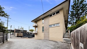 A two-story building with a flat roof, a brick facade, and a gated entrance. - Balcony 2-Bed Apartment in Ashgrove (Ashgrove)