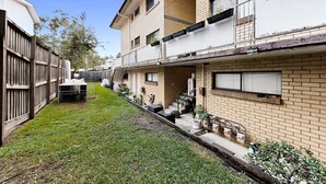 A residential building with a small front yard, a wooden fence, and a staircase leading to the entrance. - Balcony 2-Bed Apartment in Ashgrove (Ashgrove)