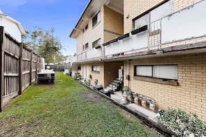 A residential building with a small front yard, a wooden fence, and a staircase leading to the entrance. - Balcony 2-Bed Apartment in Ashgrove (Ashgrove)