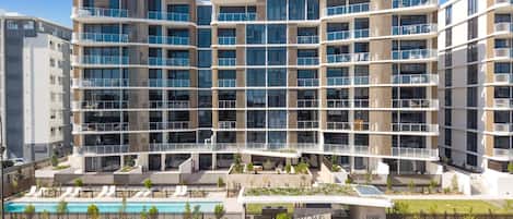 Un hôtel moderne à plusieurs étages, doté d’une piscine, d’un espace extérieur aménagé pour s’asseoir et d’un jardin paysager.