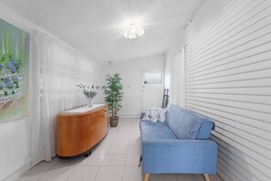 Ein modernes Wohnzimmer mit einem blauen Sofa, einem Holzschrank, einer Topfpflanze und einem Bild an der Wand.