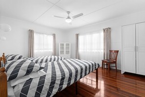 Ein Schlafzimmer mit einem Bett, einem Sessel, einem Kleiderschrank und einem Deckenventilator.