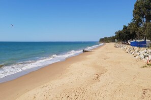 Ein Strand mit blauem Himmel, ruhiger See und felsigem Ufer.