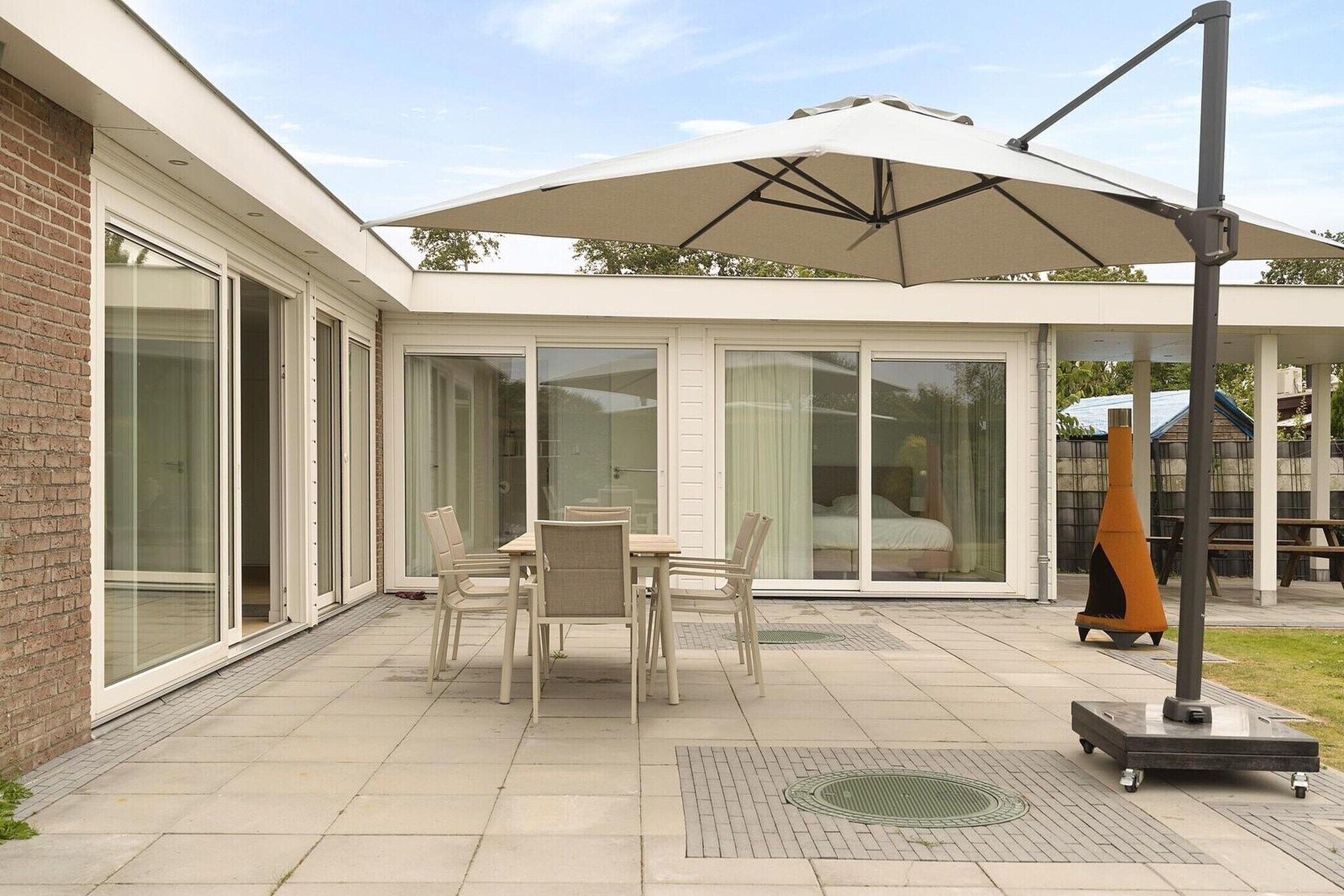A patio with a table and chairs, a large umbrella, and a decorative cone.
