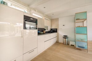 Eine moderne Küche mit weißen Schränken, einem eingebauten Backofen und einer Kaffeemaschine auf der Arbeitsfläche.