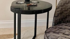 A round table with a bottle and two glasses, a blue decorative object on the wall, and a white lamp. - Tenuta Legaro (Monopoli)