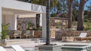 A poolside area with lounge chairs, a pergola, and a stone wall. - Tenuta Legaro (Monopoli)