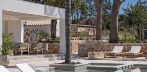 A poolside area with lounge chairs, a pergola, and a stone wall. - Tenuta Legaro (Monopoli)