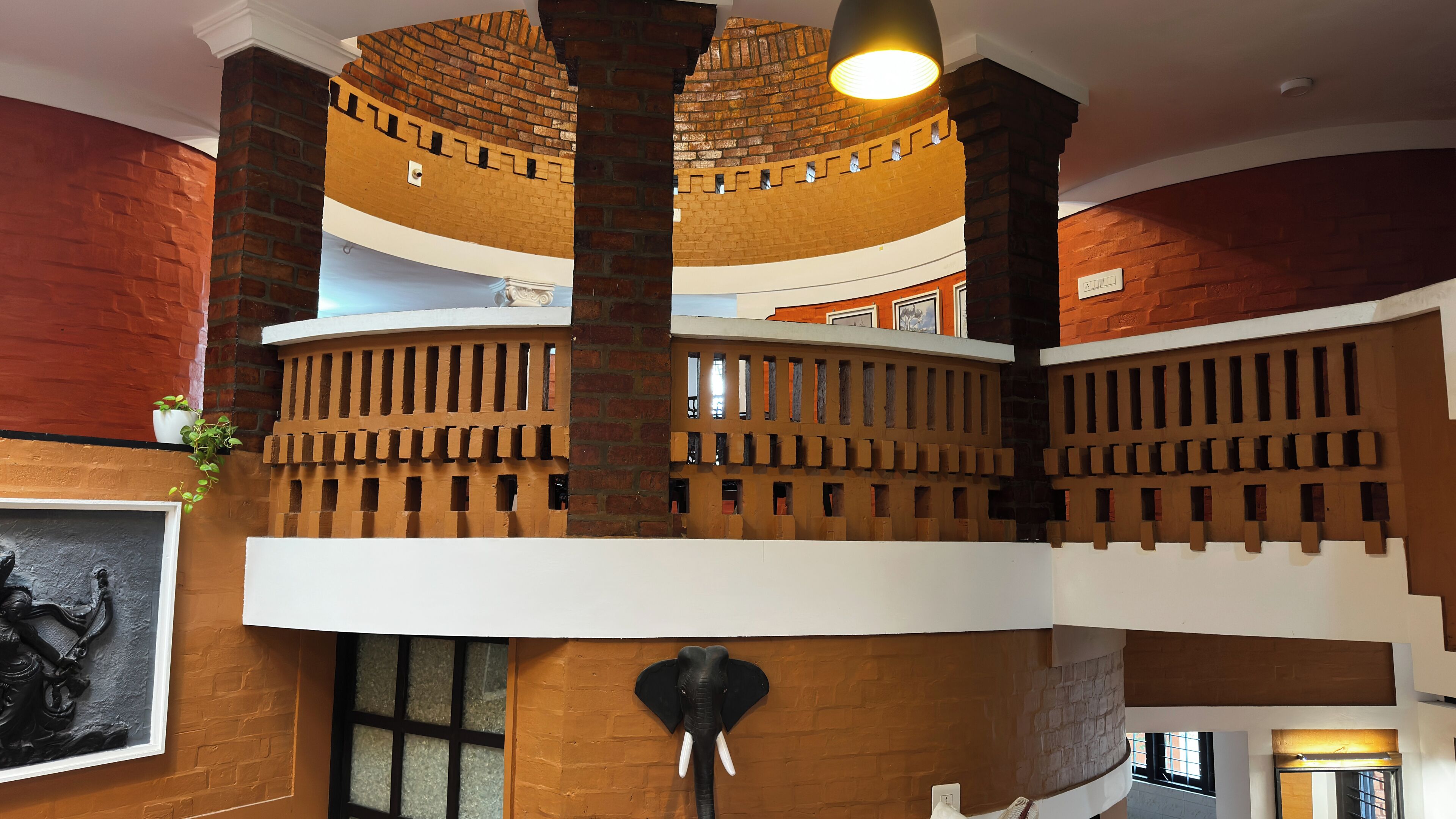 A multi-level interior with brick walls, a decorative elephant sculpture, and a staircase.