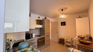 Eine kompakte Küche mit modernen Geräten, ein Essbereich mit Tisch und Stühlen und ein kleiner Hocker.