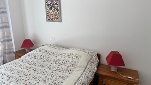 Ein Schlafzimmer mit einem Bett, zwei Nachttischen, einer Lampe auf jedem Tisch und einem an der Wand montierten Lichtschalter.