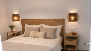 A bedroom with a wooden bed, two bedside tables, a nightstand, a wall-mounted lamp, a floor lamp, and a door. - Vacation Home 'Casa Del Mar' with Shared Pool, Private Garden and Wi-Fi (Costa Calma)