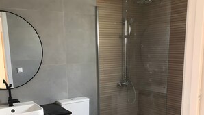 A modern bathroom with a toilet, sink, and shower. - Vacation Home 'Casa Del Mar' with Shared Pool, Private Garden and Wi-Fi (Costa Calma)
