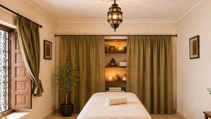 Una habitación con una cama, una lámpara colgante, una planta en maceta y una repisa con velas.