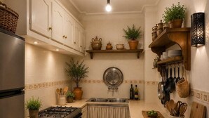 Cocina con estufa, fregadero y armarios. Hay plantas y utensilios de cocina sobre las encimeras.
