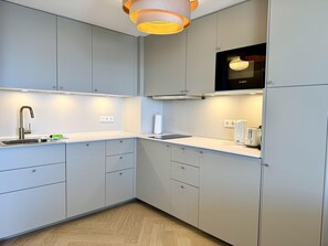 A modern kitchen with grey cabinets, a stainless steel sink, and a Bosch microwave. - Ocean View - Modern apartment, balcony with ocean view, parking space, Wi-Fi. Pets (Sylt)