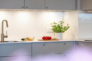 A modern kitchen with a stainless steel faucet, a potted plant, and fresh vegetables on the counter. - Ocean View - Modern apartment, balcony with ocean view, parking space, Wi-Fi. Pets (Sylt)