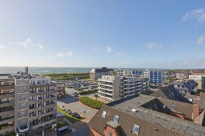 A coastal residential area with multi-story buildings, a parking lot, and a view of the sea. - Ocean View - Modern apartment, balcony with ocean view, parking space, Wi-Fi. Pets (Sylt)