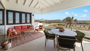 Un balcon spacieux, agrémenté d’un canapé, de chaises et d’une table, offrant une vue imprenable sur un paysage magnifique.