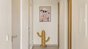 Un couloir décoré avec des cactus et orné d’une œuvre d’art encadrée au mur.