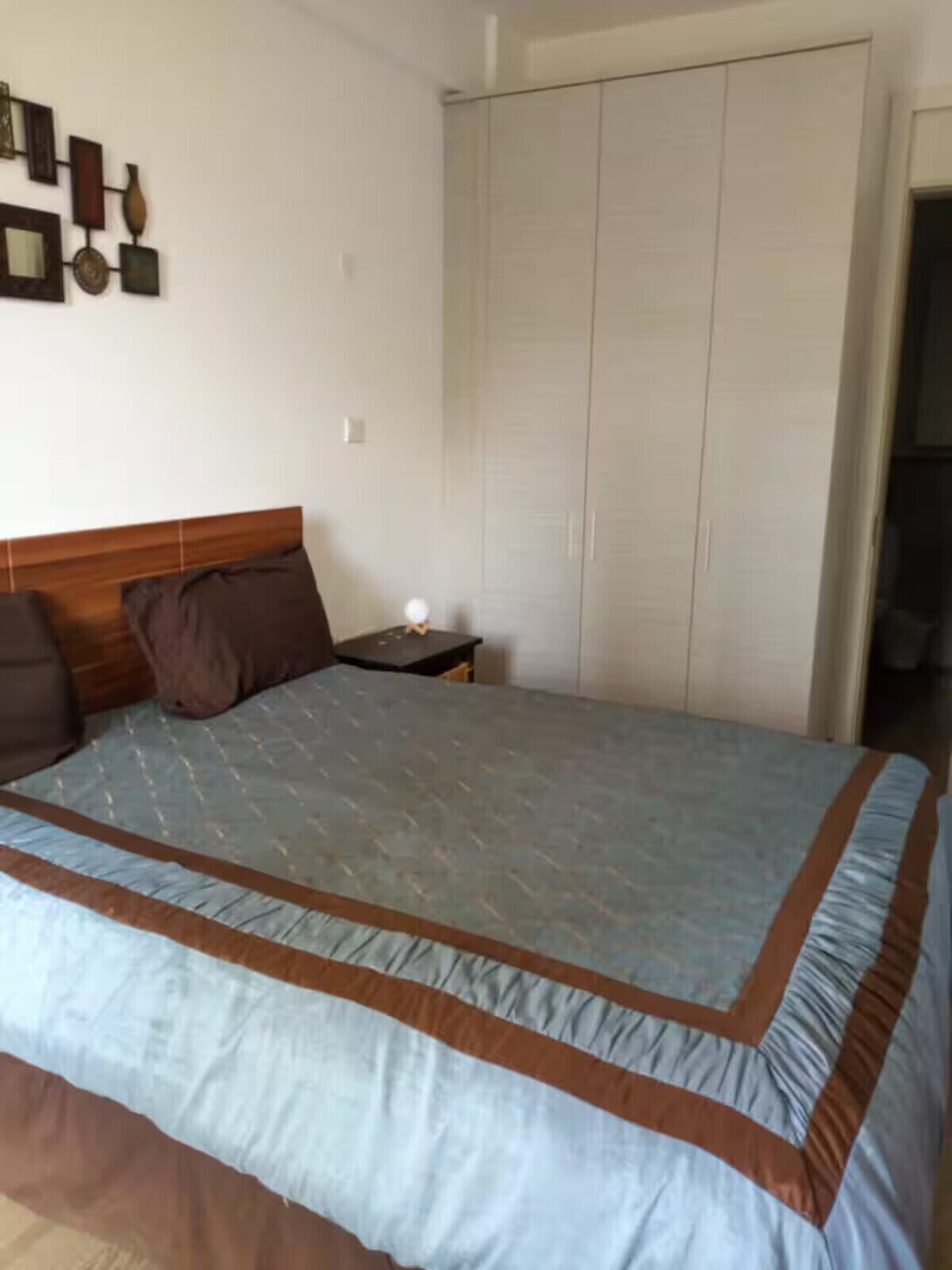 Ein Schlafzimmer mit einem Bett, einem Nachttisch, einem Kleiderschrank und Wanddekoration.