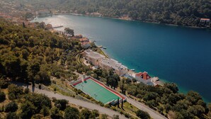 An aerial view of a coastal area with a tennis court, buildings, and a body of water. - Luxury Villa Katino Estate with Private Pool & Sea Views (Šipanska Luka)
