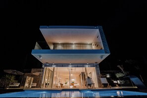 Un edificio moderno de dos pisos con una piscina frente a él.