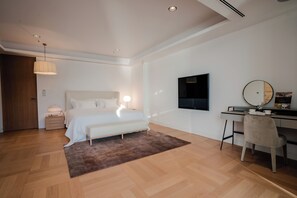 Ein modernes Schlafzimmer mit Bett, Nachttisch, Lampe und einem Schreibtisch mit Stuhl.