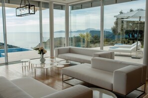 A modern living room with a large window overlooking a scenic view. - Luxury Villa Katino Estate with Private Pool & Sea Views (Šipanska Luka)