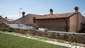 Un edifici residencial amb teulada de teules, parets de pedra i una petita zona de jardí amb un camí.
