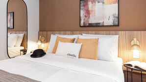 Een hotelkamer met een bed, een spiegel, een kunstwerk aan de muur en bedlampjes.