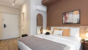 Quarto de hotel com cama, mesa de cabeceira, luminária e um quadro na parede.