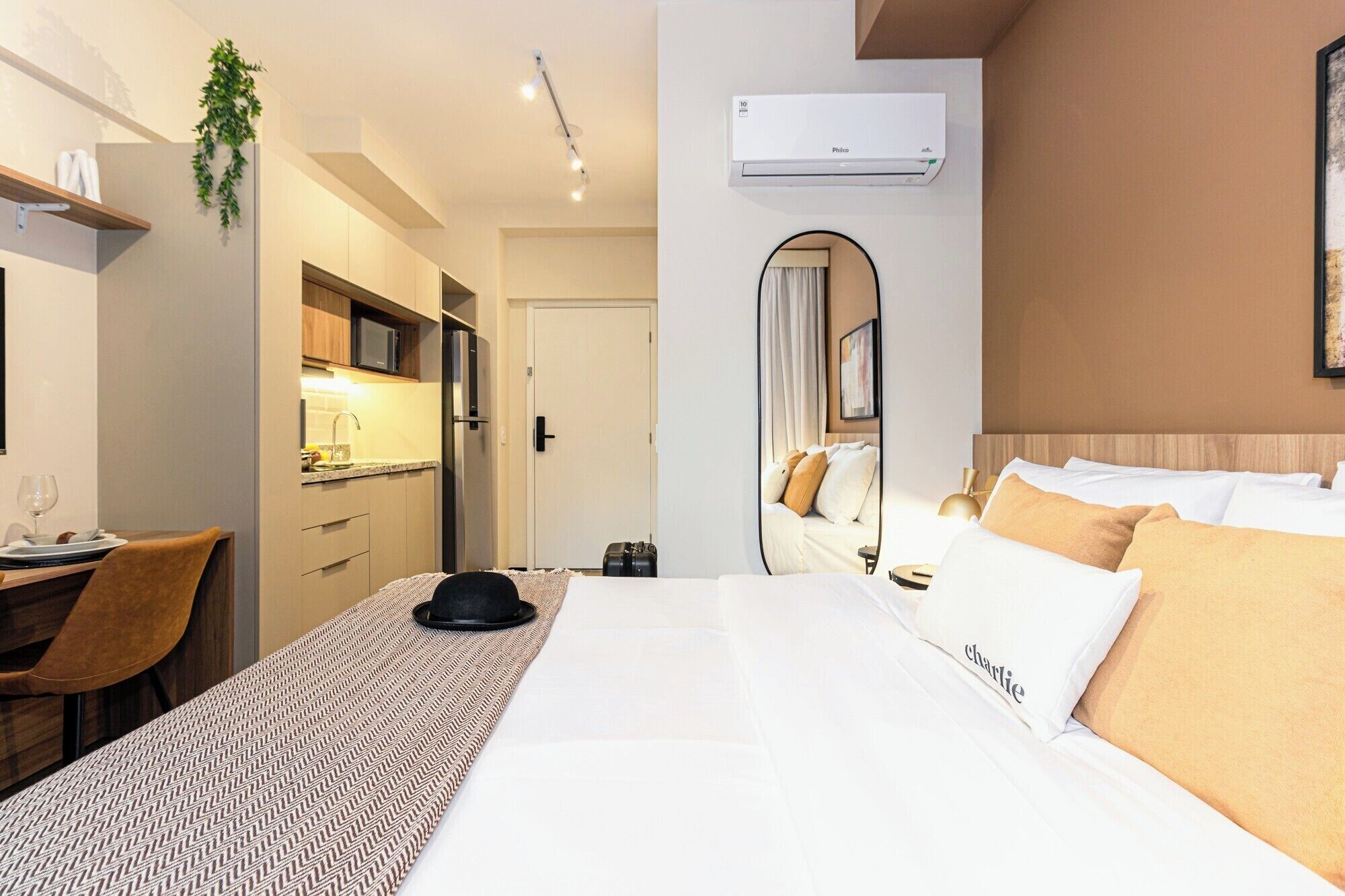 Ein Hotelzimmer mit Bett, Schreibtisch, Stuhl, Spiegel und einer Küchenzeile.