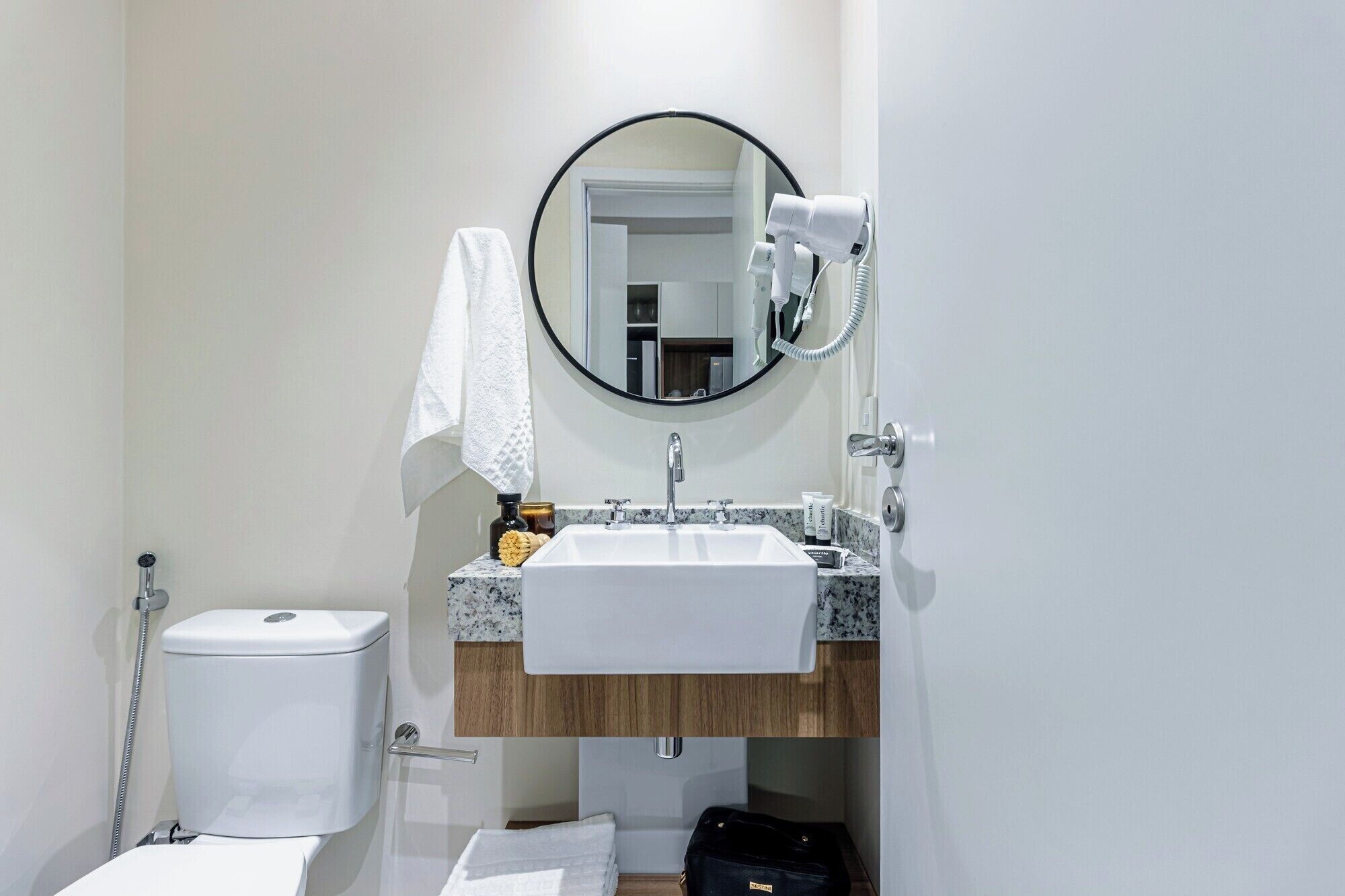 A bathroom with a toilet, sink, and mirror.