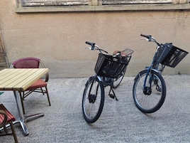 Dos bicicletas con cestas, una mesa con un banco y una silla.