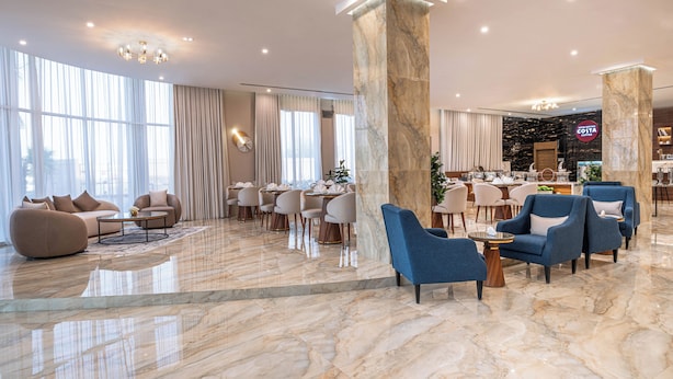 A spacious lobby with a marble floor, seating areas, and a coffee bar.