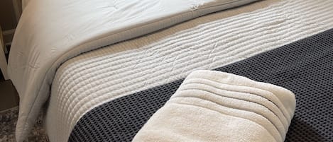 Una cama bien hecha con cabecera, varias almohadas y una manta.