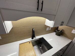 Une cuisine équipée d’un évier, d’une planche à découper et d’un mortier avec un pilon.