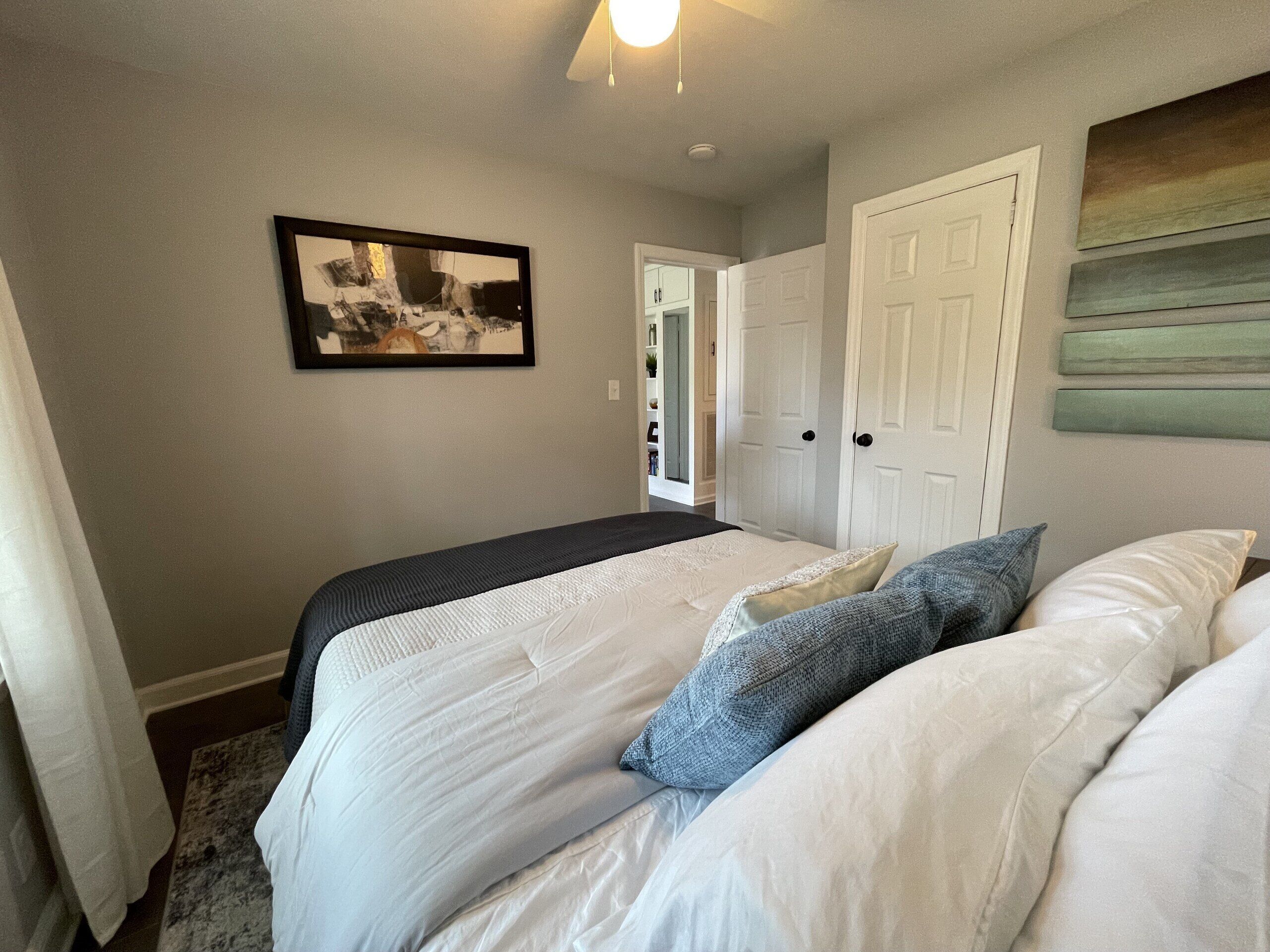 Ein Schlafzimmer mit einem Bett, einer Tür und einem gerahmten Bild an der Wand.