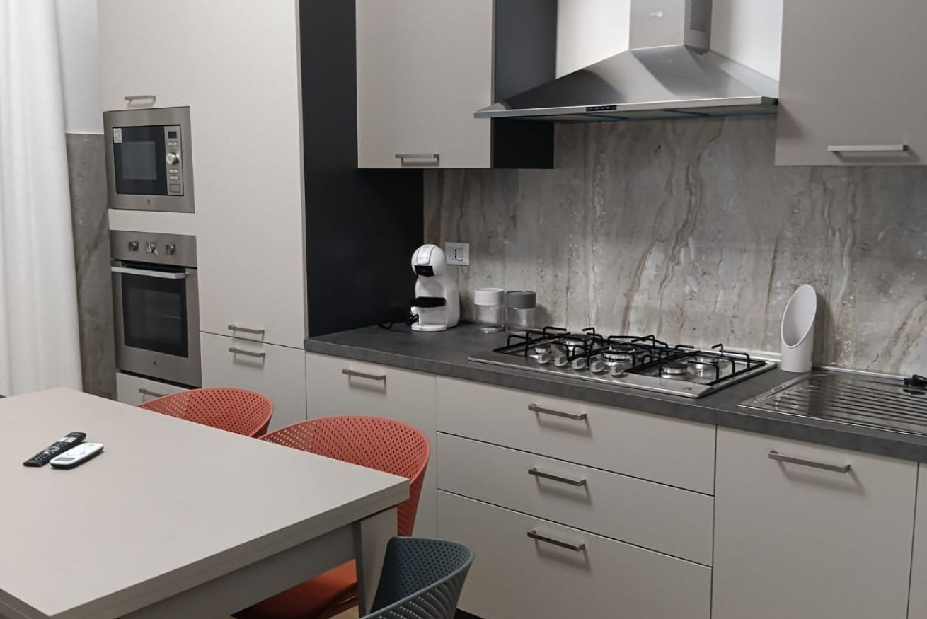 Eine moderne Küche mit eingebauten Geräten, ein Essbereich mit zwei Stühlen und einer Marmor-Spritzschutzwand.