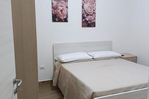 A bedroom with a bed, a nightstand, and two wall-mounted floral paintings.