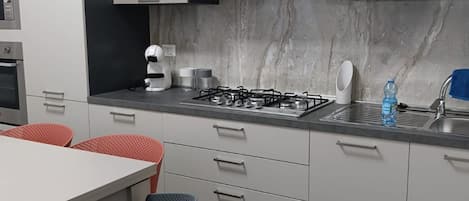 A modern kitchen with a gas stove, white cabinets, and a marble backsplash.