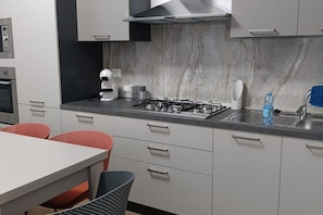 A modern kitchen with a gas stove, white cabinets, and a marble backsplash.