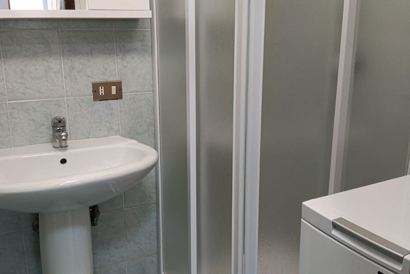 Une salle de bain avec un lavabo blanc, un miroir au-dessus et un meuble blanc sur le côté droit.