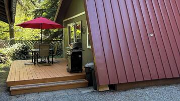 A small cabin with a wooden deck and a red umbrella.